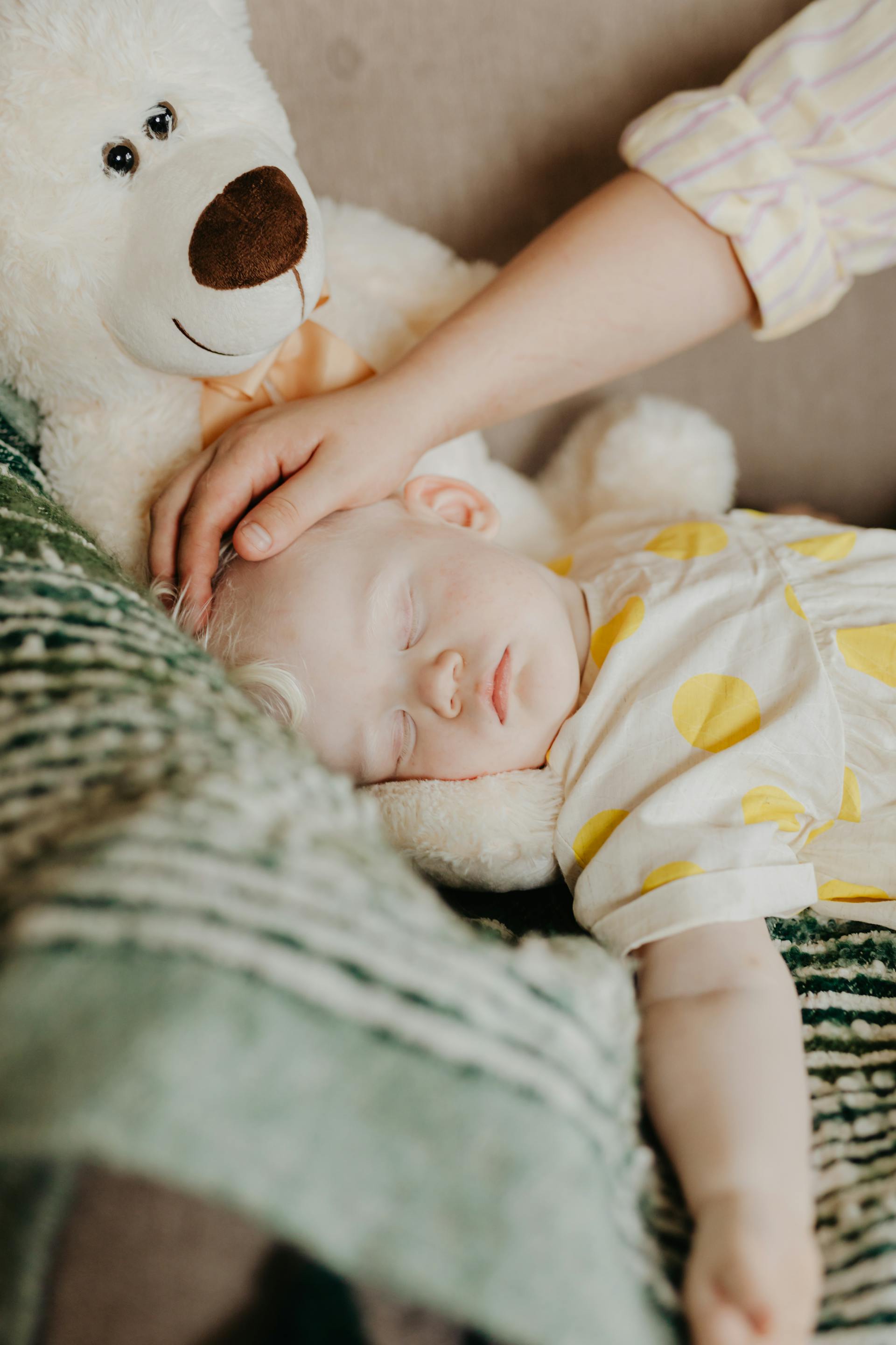 A mother carresses the head of her peacefully sleeping baby